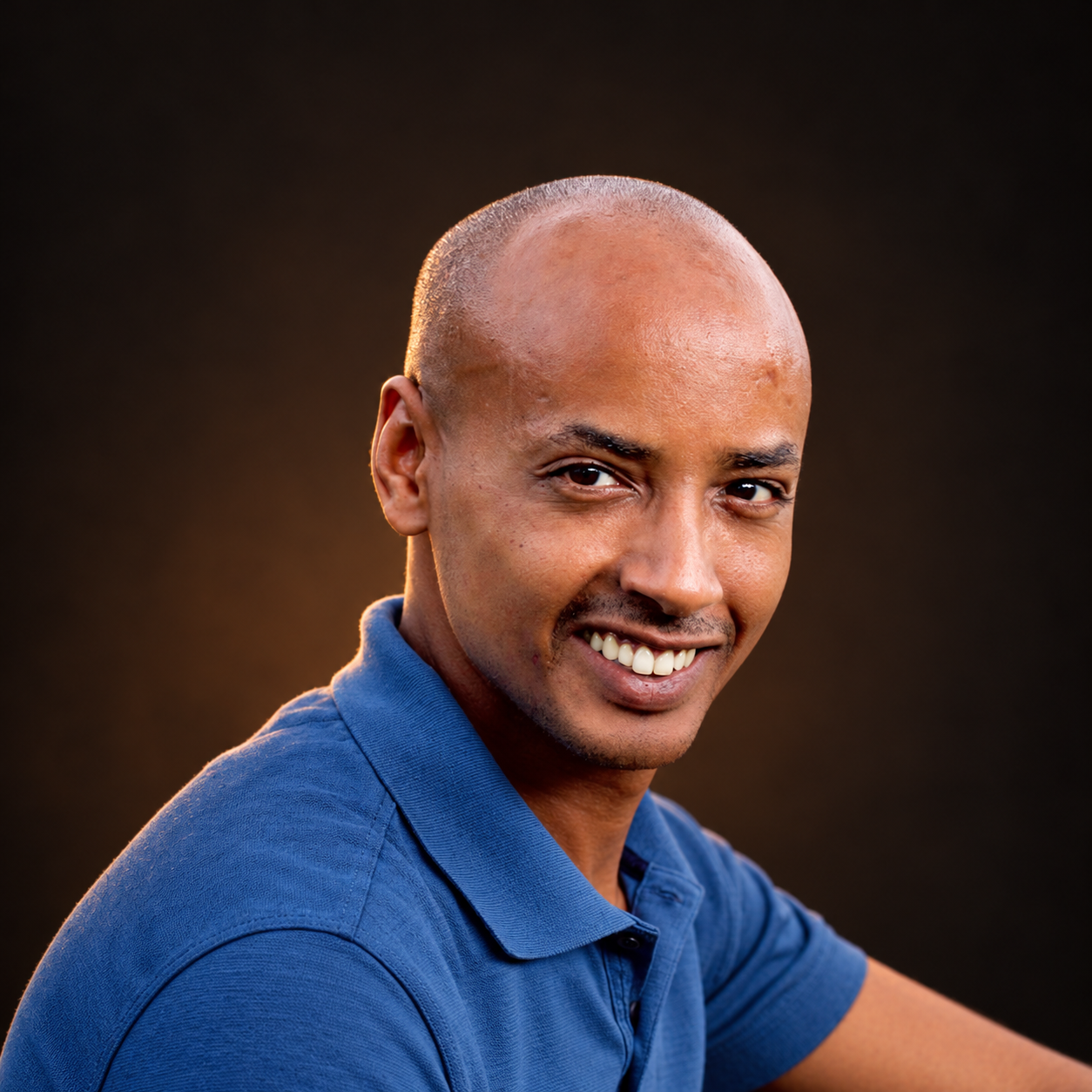 Guy T, creator of ForYourSoul, smiling at the camera in warm amber light